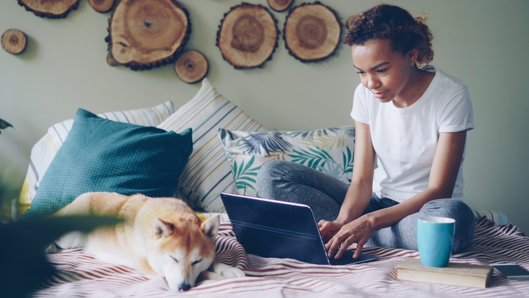 Thuiswerker met hond naast de laptop op de bank